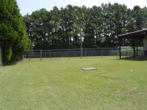 A field with trees in the background and a baseball diamond.